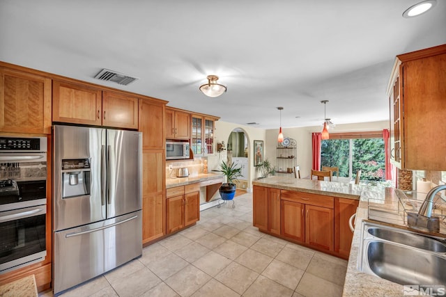 3295 Sunnyvale Ave, Reno, NV 89509 - kitchen with appliances with stainless steel finishes, arched walkways, a sink, and brown cabinetry