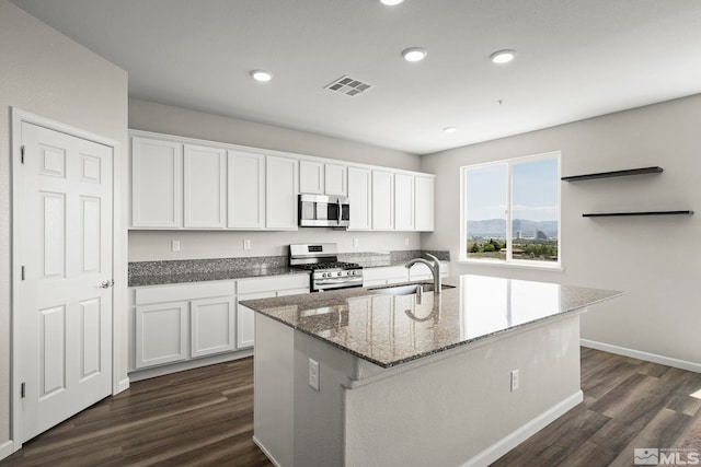 kitchen featuring appliances with stainless steel finishes, a sink, white cabinetry, dark wood-style floors, and dark stone counters