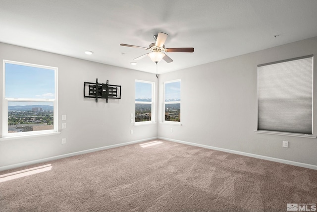 spare room featuring carpet, baseboards, and ceiling fan