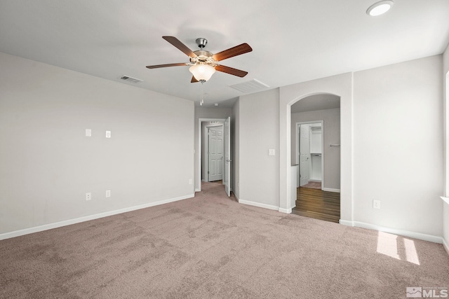 unfurnished bedroom featuring arched walkways, carpet, baseboards, and a ceiling fan