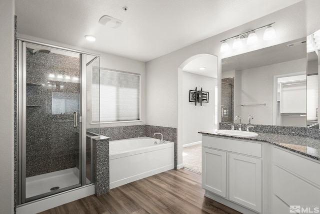 bathroom with a shower stall, a garden tub, wood finished floors, and vanity