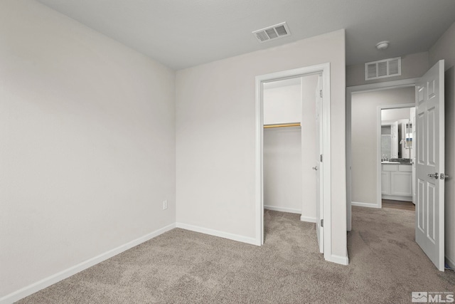 unfurnished bedroom with carpet, baseboards, a closet, and a spacious closet