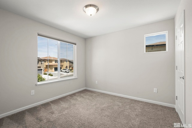 carpeted empty room featuring baseboards