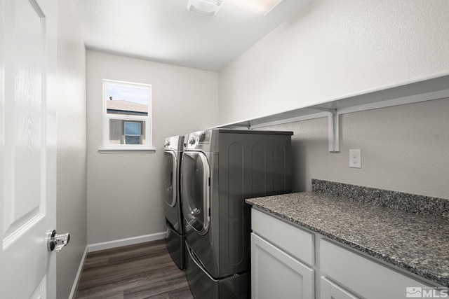 clothes washing area with washing machine and clothes dryer, dark wood-style flooring, and baseboards