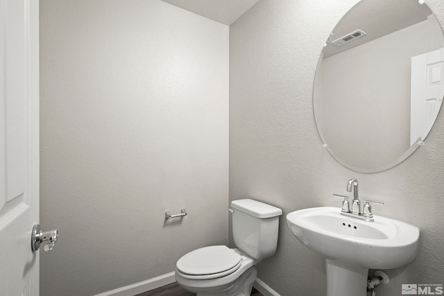 bathroom with toilet, a sink, and baseboards