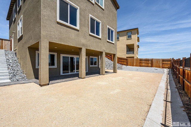 rear view of property with stucco siding, a fenced backyard, and a patio