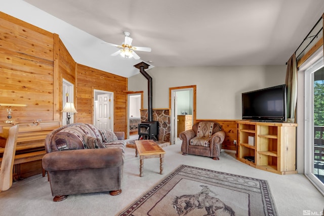 14865 N Red Rock Rd, Reno, NV 89508 - living room featuring wood walls, carpet flooring, a wood stove, ceiling fan, and vaulted ceiling