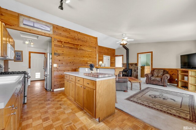 14865 N Red Rock Rd, Reno, NV 89508 - kitchen featuring appliances with stainless steel finishes, a wood stove, wood walls, open floor plan, and a kitchen bar
