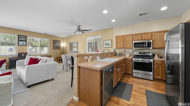 1230 Quail Run Dr, Carson City, NV 89701 - kitchen featuring stainless steel appliances, a sink, open floor plan, a peninsula, and brown cabinets