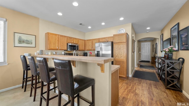 1230 Quail Run Dr, Carson City, NV 89701 - kitchen with stainless steel appliances, arched walkways, a peninsula, light countertops, and baseboards