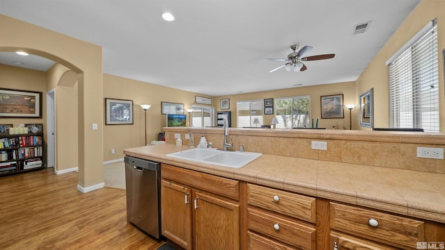 1230 Quail Run Dr, Carson City, NV 89701 - kitchen featuring stainless steel dishwasher, a sink, arched walkways, a ceiling fan, and light wood-style flooring