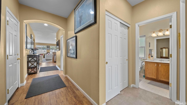 1230 Quail Run Dr, Carson City, NV 89701 - hallway with light wood-style floors, arched walkways, baseboards, and a sink
