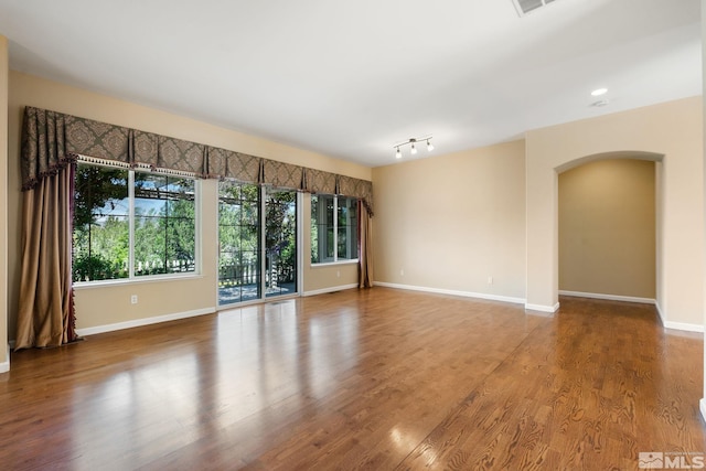 1745 Hunter Creek Rd, Reno, NV 89519 - empty room featuring arched walkways, plenty of natural light, baseboards, and wood finished floors