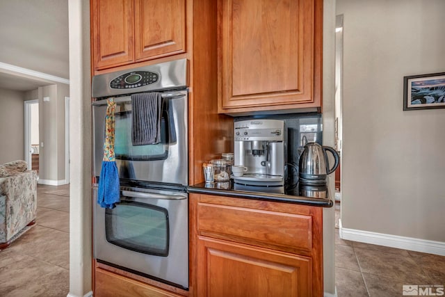 2825 N Fork Ln, Minden, NV 89423 - kitchen with stainless steel double oven, baseboards, tile patterned flooring, dark countertops, and brown cabinetry