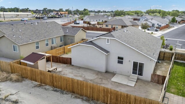 1282 Onda Verde Dr, Fallon, NV 89406 - rear view of property featuring a shingled roof, a residential view, a fenced backyard, stucco siding, and a patio area