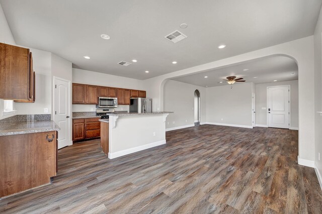 1282 Onda Verde Dr, Fallon, NV 89406 - kitchen with stainless steel appliances, arched walkways, brown cabinets, a center island, and dark wood-style flooring