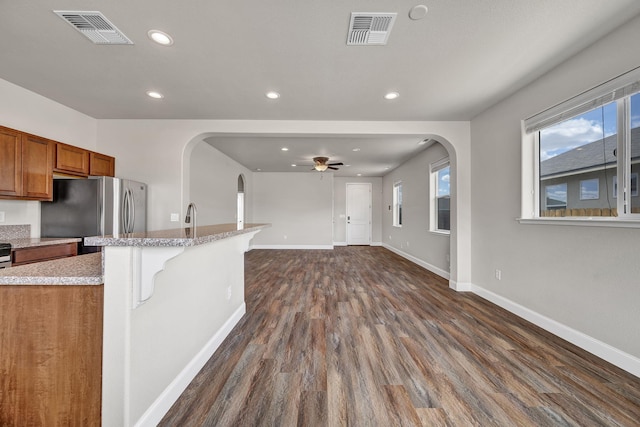 1282 Onda Verde Dr, Fallon, NV 89406 - kitchen with freestanding refrigerator, brown cabinetry, arched walkways, recessed lighting, and dark wood-style floors