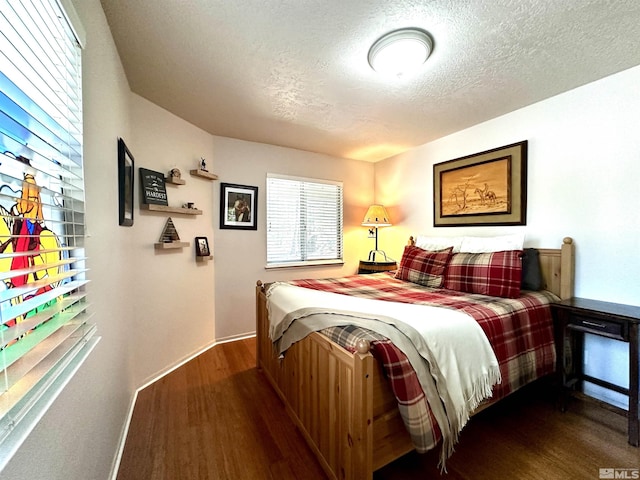 bedroom with dark wood-style flooring, a textured ceiling, and baseboards