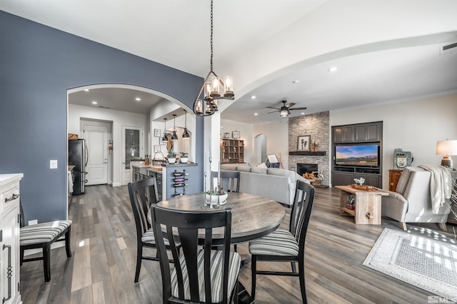 6650 Magical Dr, Sparks, NV 89436 - dining room featuring arched walkways, a ceiling fan, a stone fireplace, dark wood-style floors, and recessed lighting