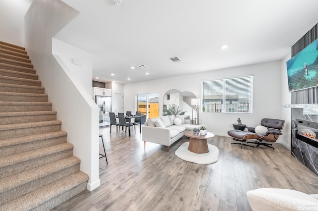 8855 Wolf Moon Dr, Reno, NV 89506 - living room with stairway, a glass covered fireplace, light wood-type flooring, arched walkways, and recessed lighting