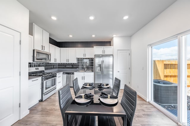 8855 Wolf Moon Dr, Reno, NV 89506 - kitchen with stainless steel appliances, white cabinetry, tasteful backsplash, light wood-style floors, and a sink