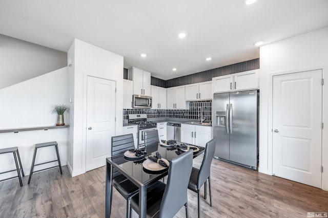 8855 Wolf Moon Dr, Reno, NV 89506 - kitchen with appliances with stainless steel finishes, white cabinets, wood finished floors, tasteful backsplash, and a sink