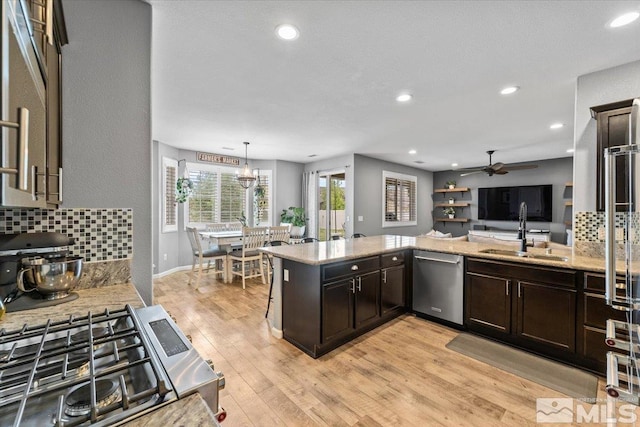 kitchen with stainless steel appliances, a sink, decorative backsplash, ceiling fan, and light stone countertops