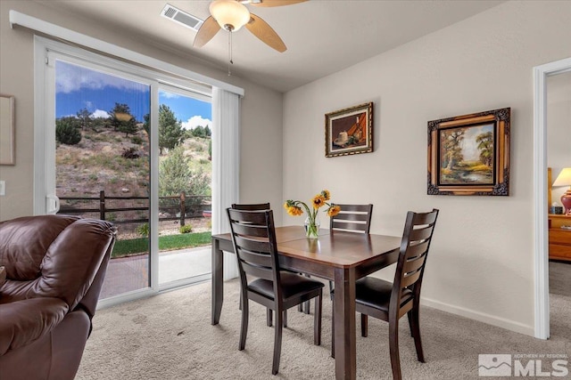 dining room featuring light colored carpet, ceiling fan, and baseboards