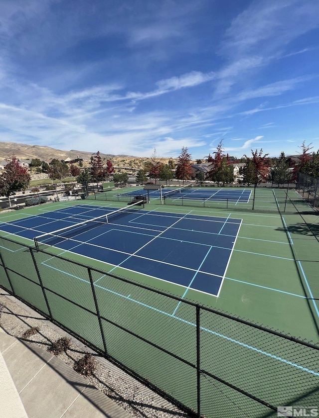 view of tennis court with fence and a mountain view