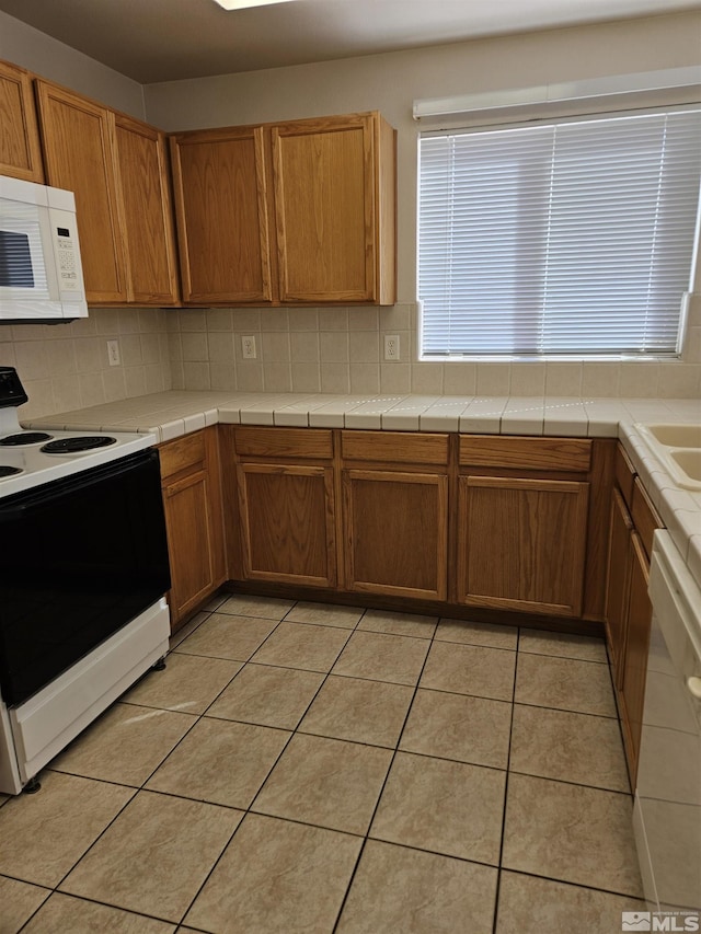 9995 Brightridge, Reno, NV 89506 - kitchen featuring white appliances, decorative backsplash, light tile patterned floors, brown cabinetry, and tile countertops