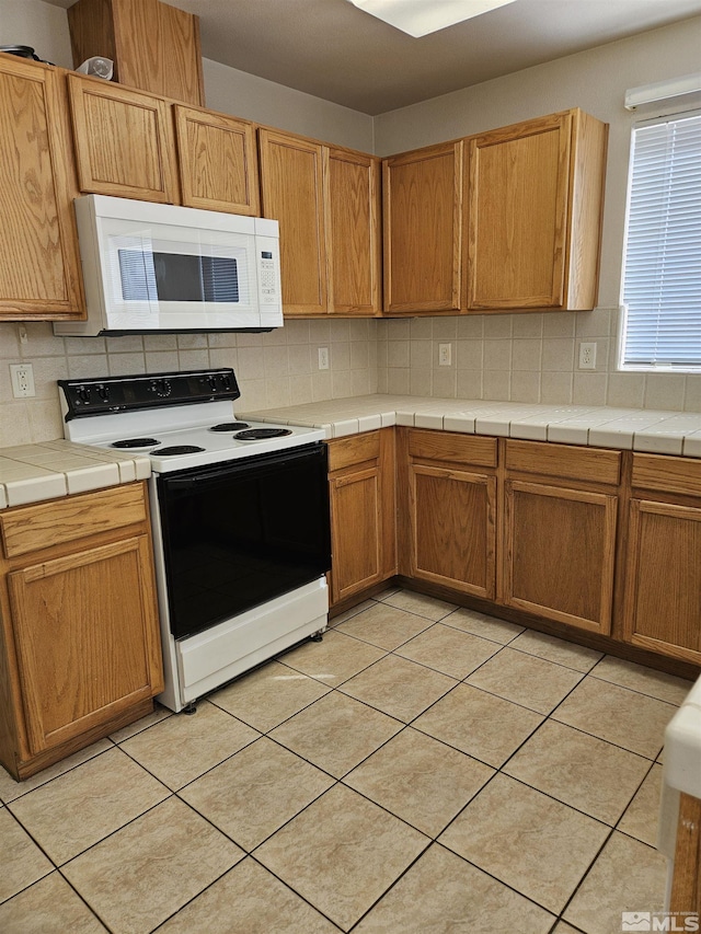 9995 Brightridge, Reno, NV 89506 - kitchen with white microwave, electric range oven, tasteful backsplash, tile countertops, and light tile patterned floors