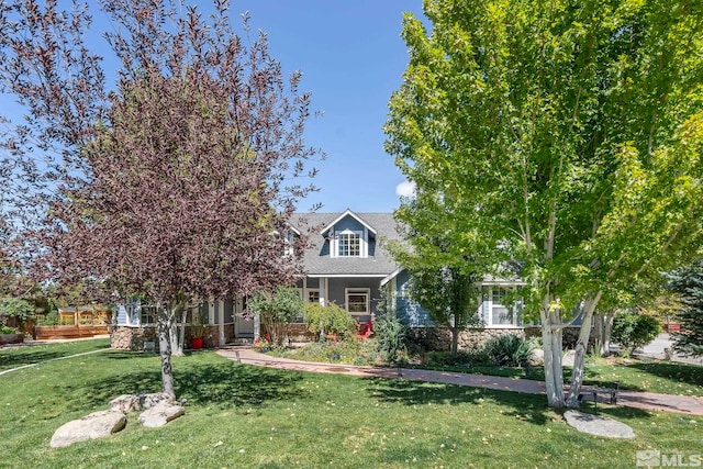 view of property hidden behind natural elements with a front lawn and stone siding