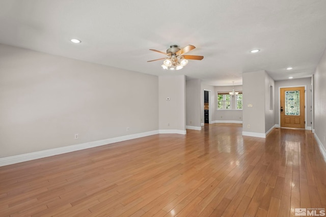 unfurnished living room with ceiling fan, baseboards, a chandelier, recessed lighting, and light wood-style flooring