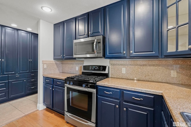 kitchen with stainless steel appliances, blue cabinetry, light countertops, decorative backsplash, and recessed lighting