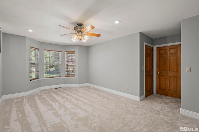 spare room featuring light colored carpet, a ceiling fan, baseboards, and recessed lighting
