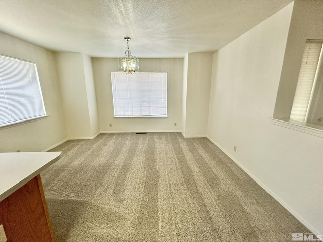 1447 N Marion Russell, Gardnerville, NV 89410 - unfurnished dining area with a chandelier, carpet floors, healthy amount of natural light, baseboards, and a textured ceiling