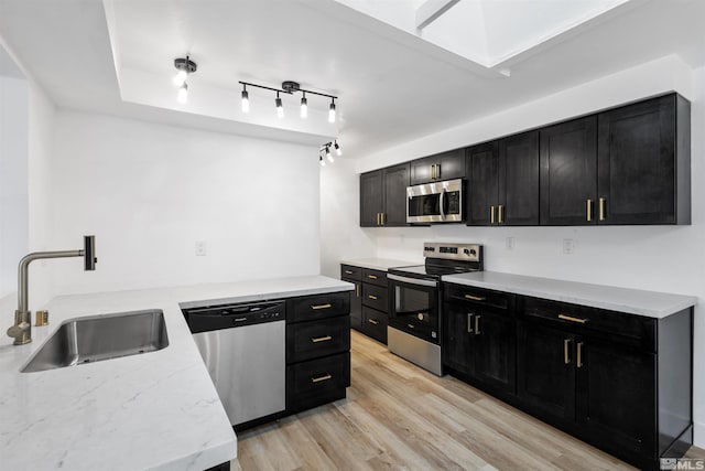 6798 Flower St, Reno, NV 89506 - kitchen featuring appliances with stainless steel finishes, dark cabinets, a sink, and light wood finished floors