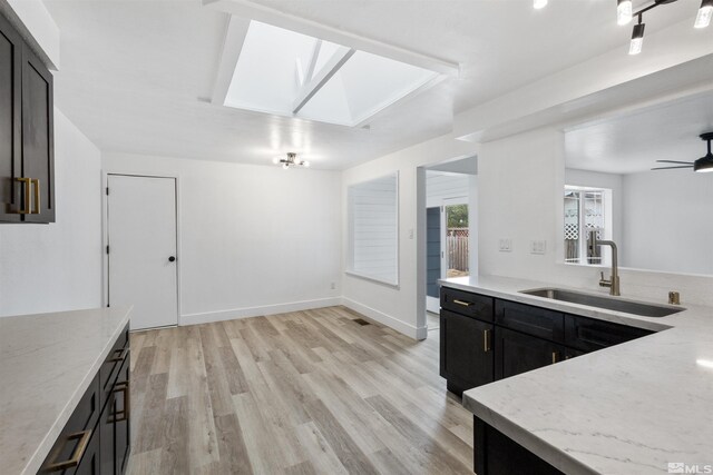 6798 Flower St, Reno, NV 89506 - kitchen with a skylight, a sink, light stone countertops, and light wood finished floors