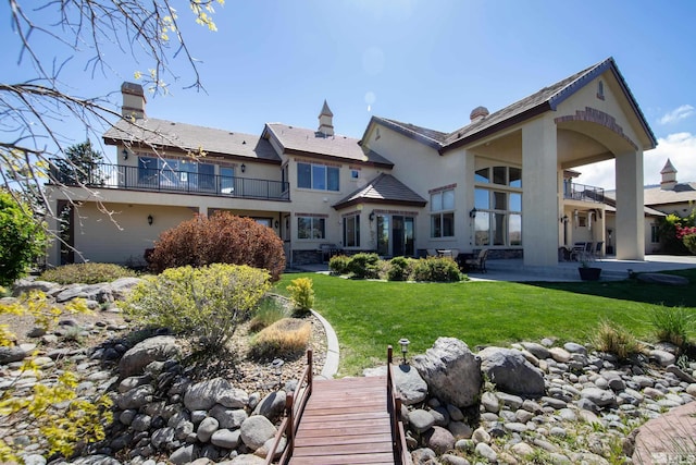 10401 Copper Cloud Dr, Reno, NV 89511 - rear view of property featuring a balcony, a patio area, a lawn, a chimney, and stucco siding