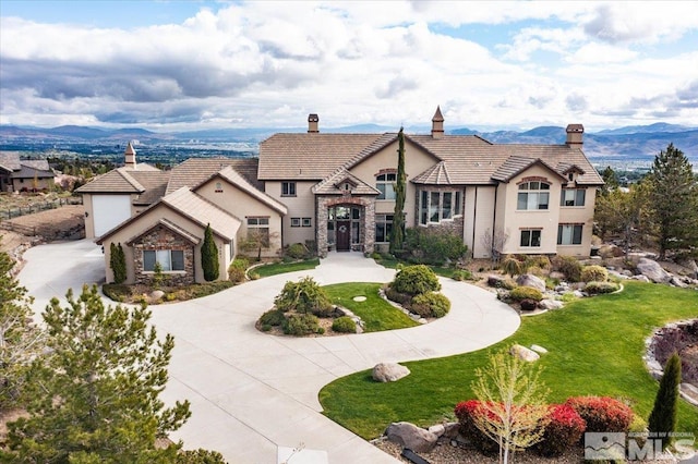 10401 Copper Cloud Dr, Reno, NV 89511 - view of front of home featuring a chimney, stone siding, curved driveway, a front lawn, and stucco siding