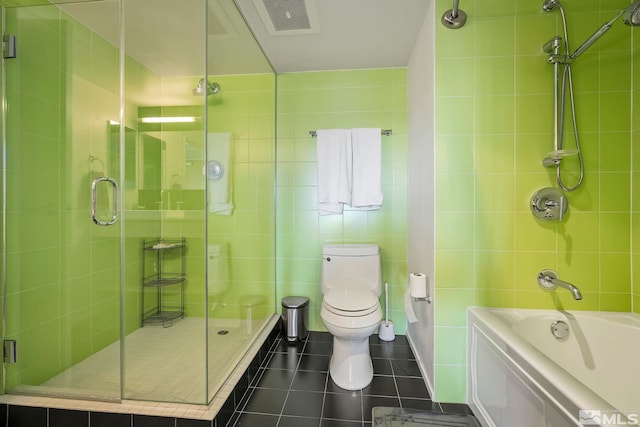 full bathroom featuring tile walls, tile patterned floors, toilet, and tiled shower / bath