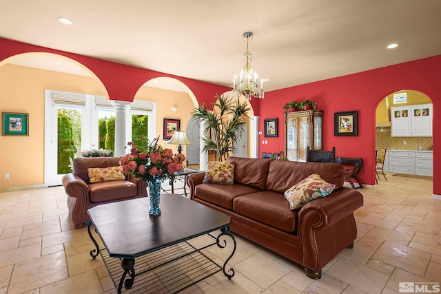 living room featuring stone tile floors, recessed lighting, a chandelier, arched walkways, and baseboards