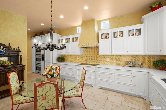 kitchen featuring custom exhaust hood, decorative backsplash, stainless steel double oven, light countertops, and white cabinets