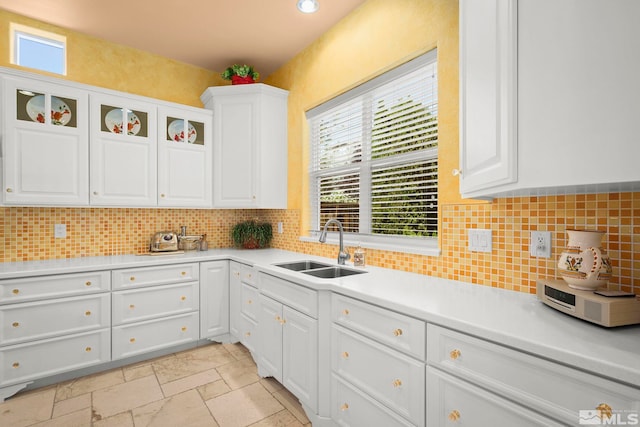 kitchen featuring a sink, white cabinets, light countertops, and decorative backsplash
