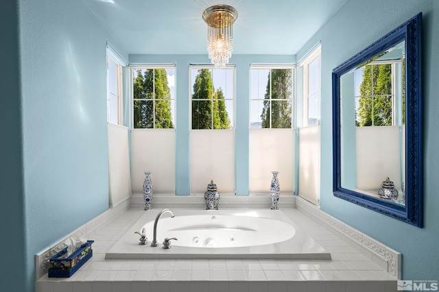 full bath with healthy amount of natural light, a tub with jets, and a chandelier