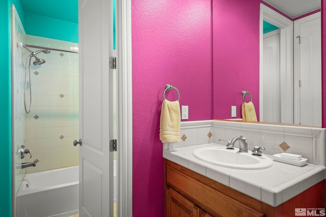 bathroom featuring a textured wall, vanity, bathtub / shower combination, and backsplash
