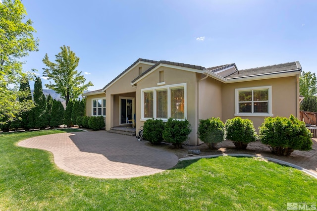 back of property with a patio, stucco siding, and a lawn