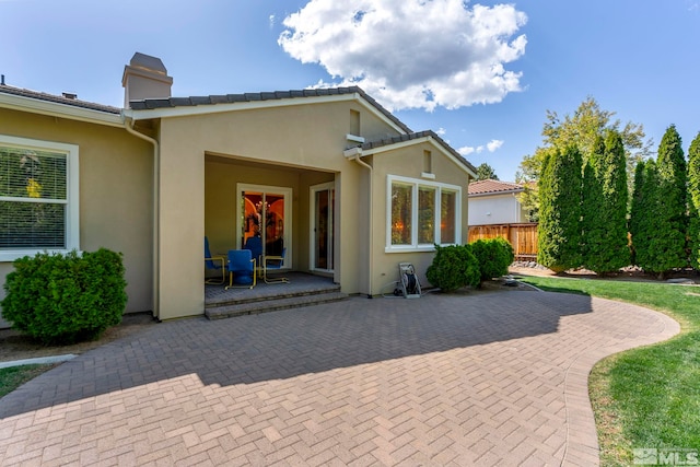 back of house with a patio area, fence, stucco siding, and a chimney