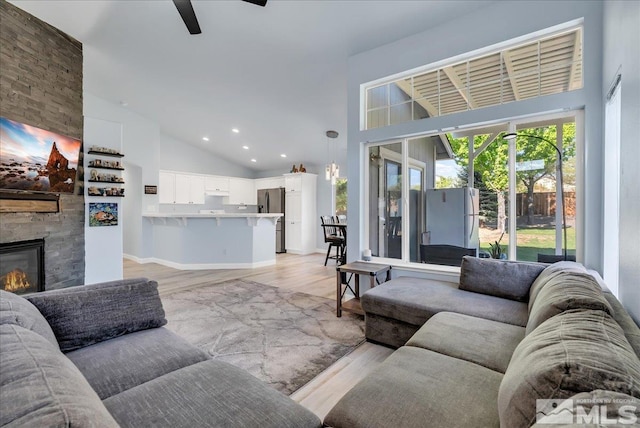 7766 Cerritos Cir, Sparks, NV 89436 - living room with high vaulted ceiling, light wood-style floors, ceiling fan, a fireplace, and recessed lighting