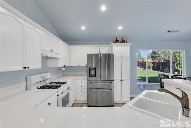 7766 Cerritos Cir, Sparks, NV 89436 - kitchen featuring stainless steel refrigerator with ice dispenser, white range with gas stovetop, a sink, under cabinet range hood, and tile counters
